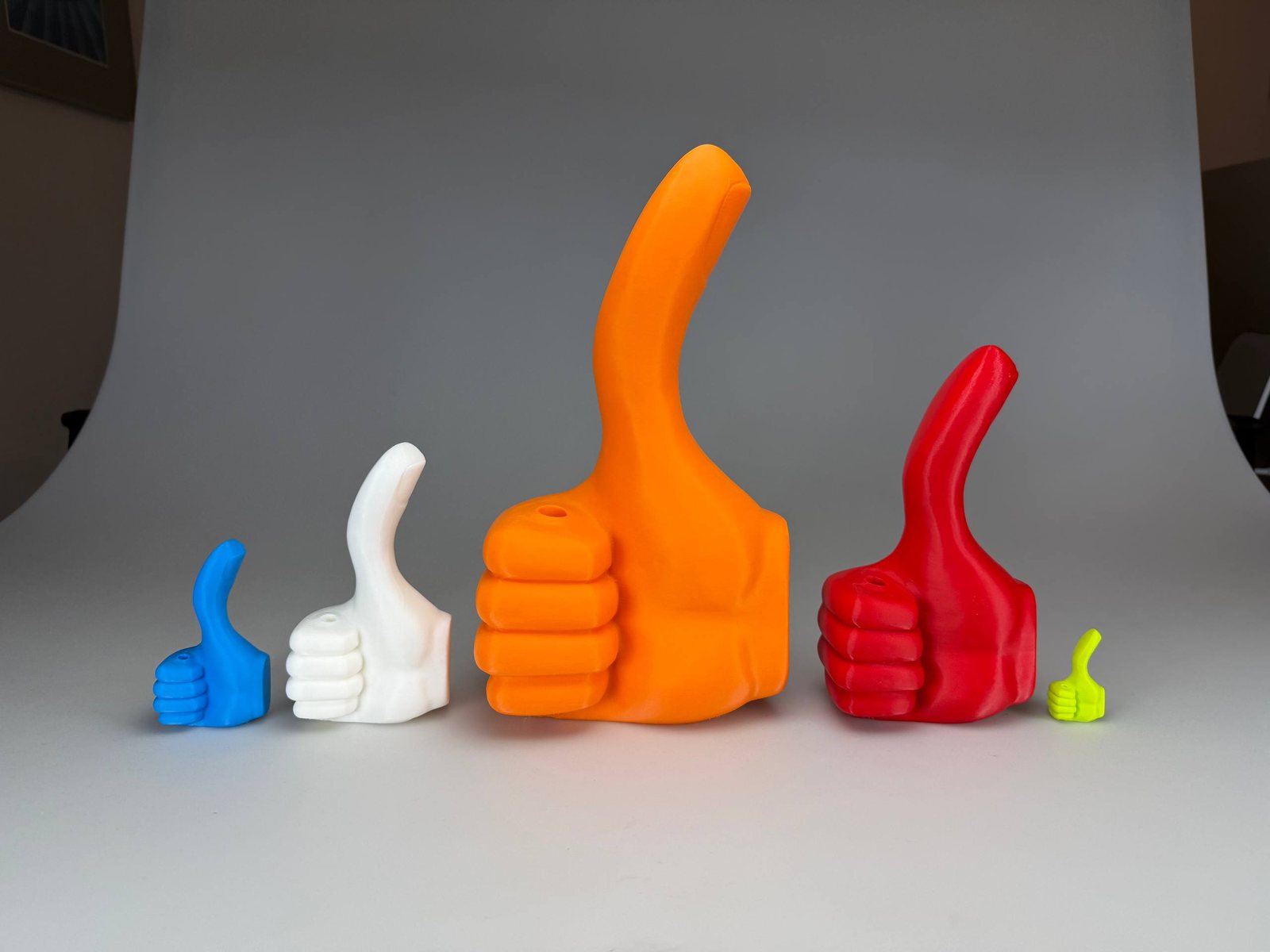 Mehrere 3D-gedruckte Daumen-hoch-Skulpturen in verschiedenen Größen und Farben