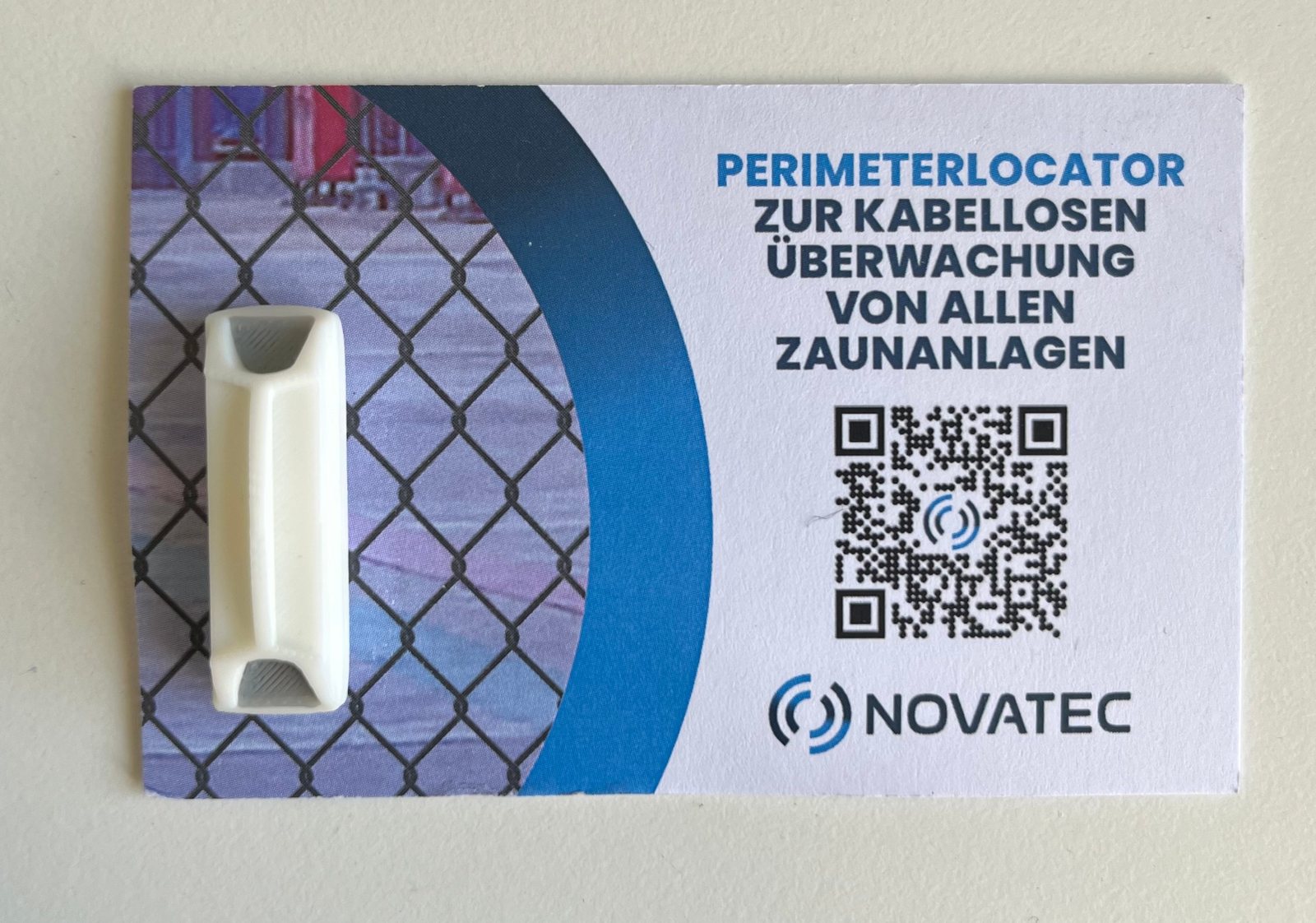 Miniatur des Novatec Perimeterlocator als Clip-Pin auf einer Visitenkarte